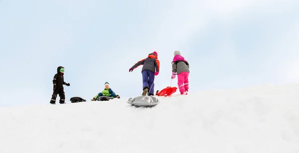 Kinderen met sleeën sneeuw heuvel klimmen in de winter — Stockfoto