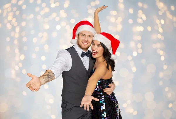 Lyckliga paret i santa hattar på julfest — Stockfoto