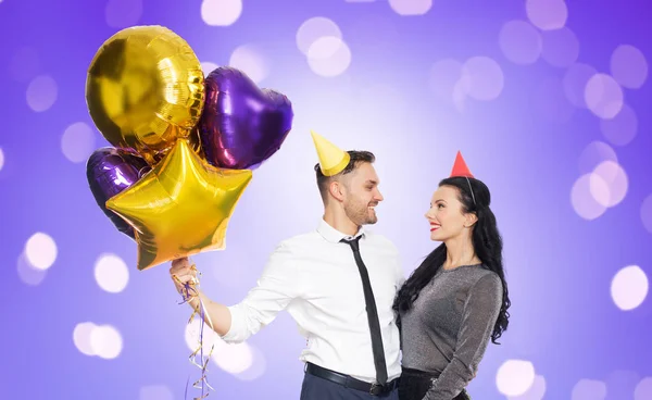 Glückliches Paar mit Partymützen und Luftballons — Stockfoto