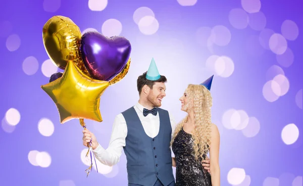 Glückliches Paar mit Partymützen und Luftballons — Stockfoto