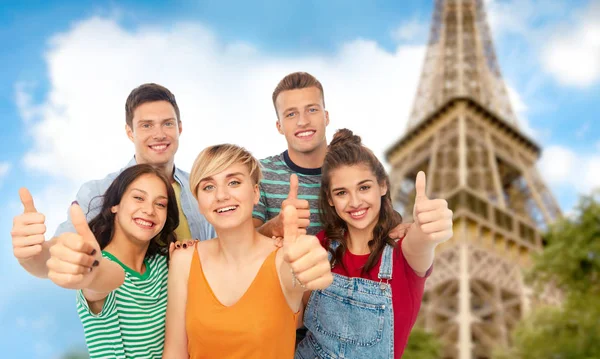 Amigos felices mostrando pulgares hacia arriba sobre la torre eiffel — Foto de Stock