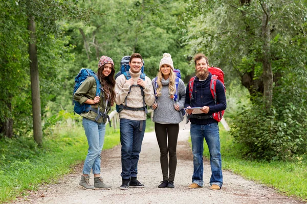 Friends or travelers hiking with backpacks and map — Stock Photo, Image