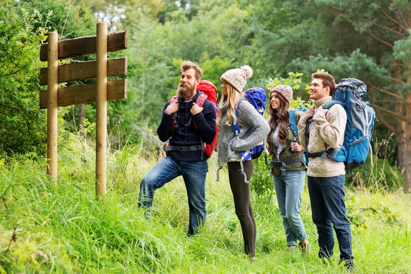 Hiking friends with backpacks at signpost — Stock Photo, Image