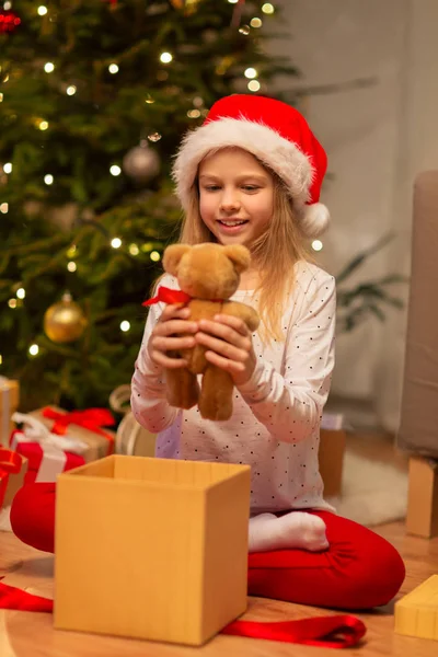 Lächelndes Mädchen mit Weihnachtsmütze und Weihnachtsgeschenk — Stockfoto