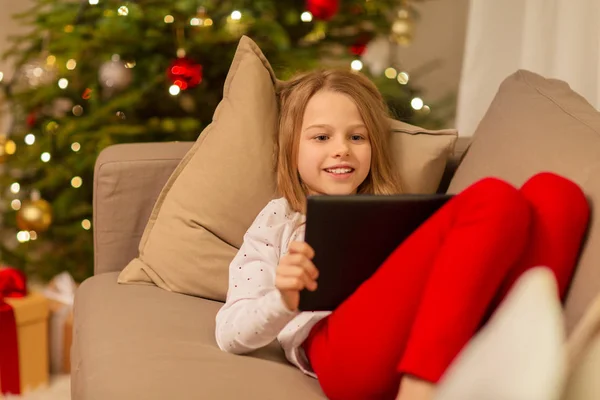 Улыбающаяся девушка с планшетным ПК на Рождество домой — стоковое фото
