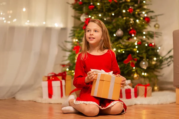 Leende flicka med julklapp hemma — Stockfoto