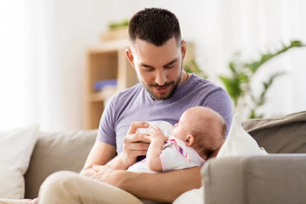 Father feeding baby daughter from bottle at home — Stock Photo, Image