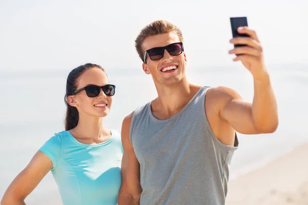 Par som tar selfie med smarttelefon på stranda – stockfoto