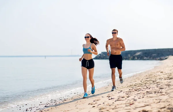 Para w ubraniach sportowych biegających wzdłuż plaży — Zdjęcie stockowe