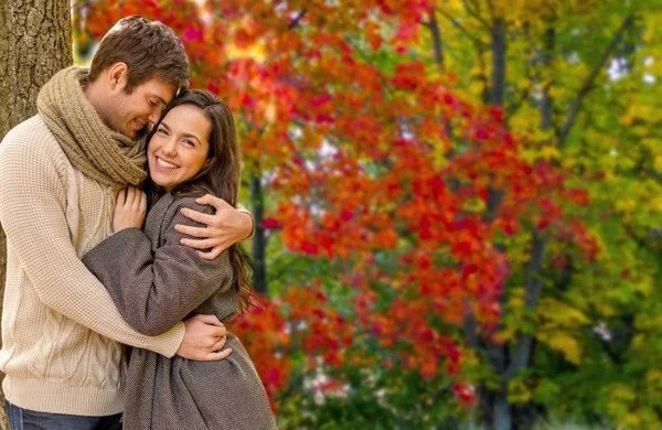 Улыбающаяся пара обнимается в осеннем парке — стоковое фото