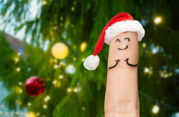 Ett finger i santa hatt över julgran — Stockfoto