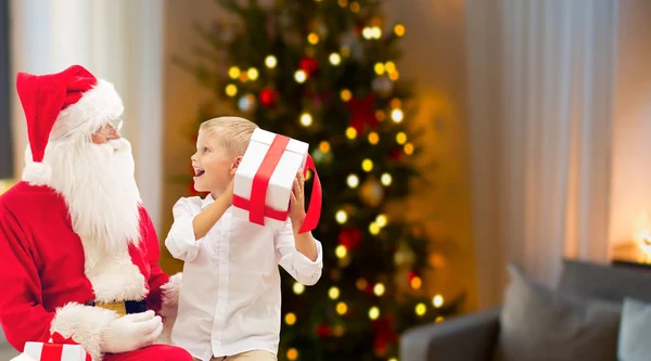 Menino e santa com presentes de Natal em casa — Fotografia de Stock