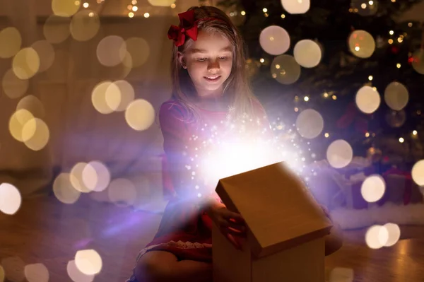 Leende flicka öppnar julklapp på natten — Stockfoto