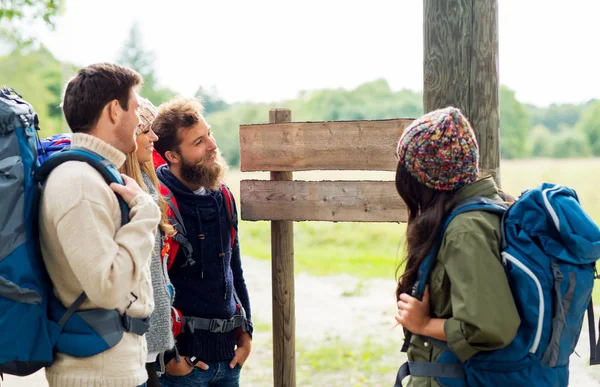 Hiking friends with backpacks at signpost — Stock Photo, Image