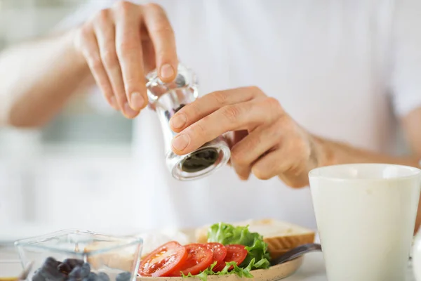 Close up of hands seasoning food by pepper mill — Stock Photo, Image