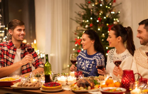Glückliche Freunde, die auf der Weihnachtsfeier Rotwein trinken — Stockfoto