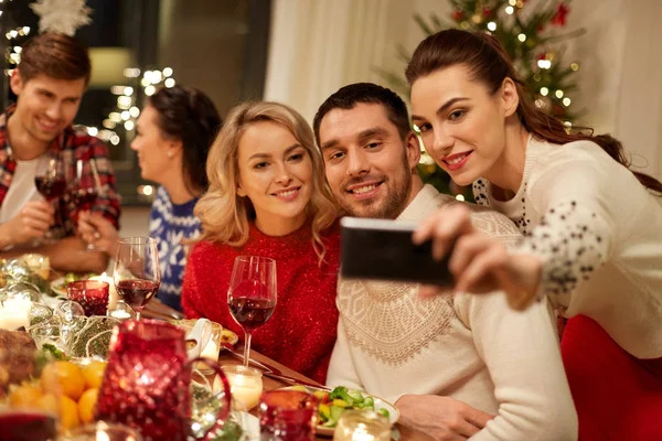 Przyjaciele mając świąteczny obiad i biorąc selfie — Zdjęcie stockowe