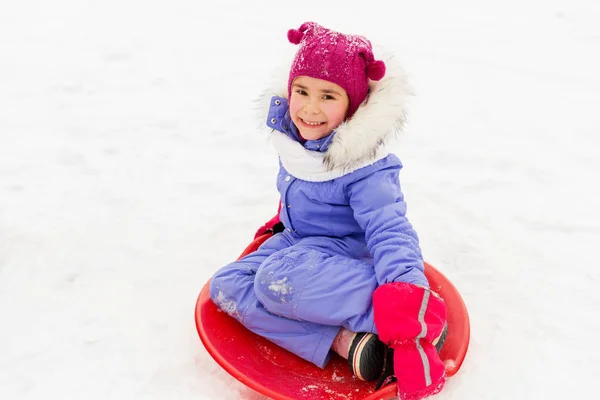 Joyeuse petite fille avec une soucoupe à neige traîneau en hiver — Photo