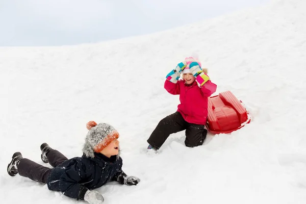 Щасливі маленькі діти з санчатами взимку на пагорбі — стокове фото