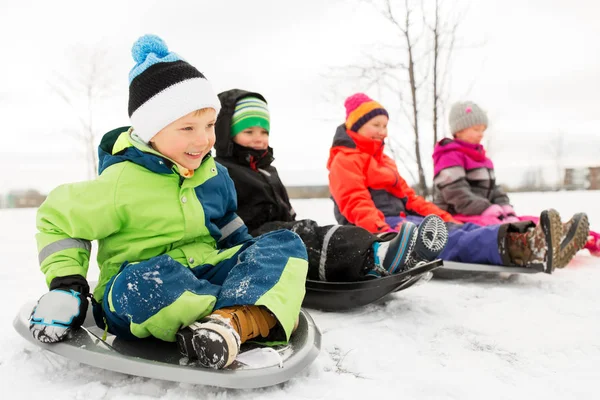 Heureux petits enfants glissant sur des traîneaux en hiver — Photo