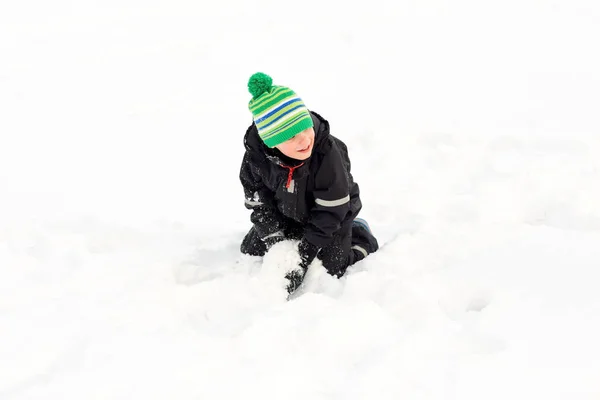 Szczęśliwy chłopiec bawi się śniegu w zimie — Zdjęcie stockowe