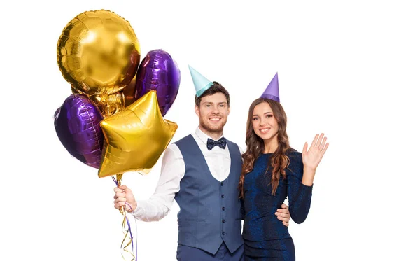 Ευτυχισμένο ζευγάρι με κόμμα καπάκια και μπαλόνια — Φωτογραφία Αρχείου