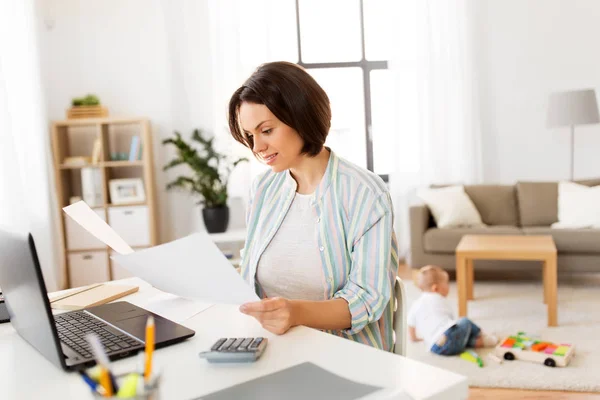 Mutter arbeitet mit Papieren und Junge zu Hause — Stockfoto