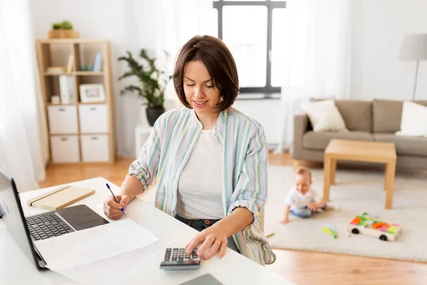 Werkende moeder rekent op Rekenmachine en baby — Stockfoto