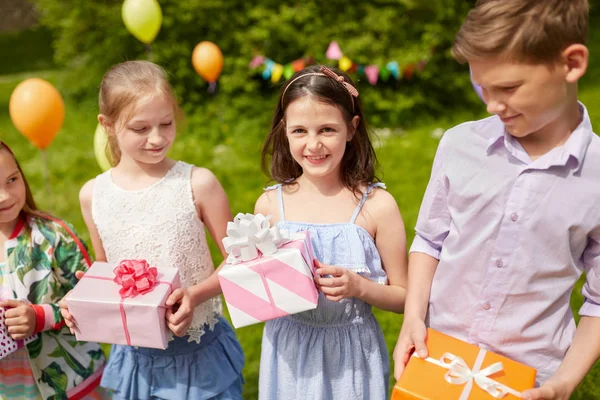 Glückliche Kinder mit Geschenken auf Geburtstagsparty im Sommer — Stockfoto