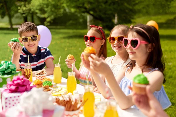 Bambini che mangiano cupcake alla festa di compleanno in estate — Foto Stock