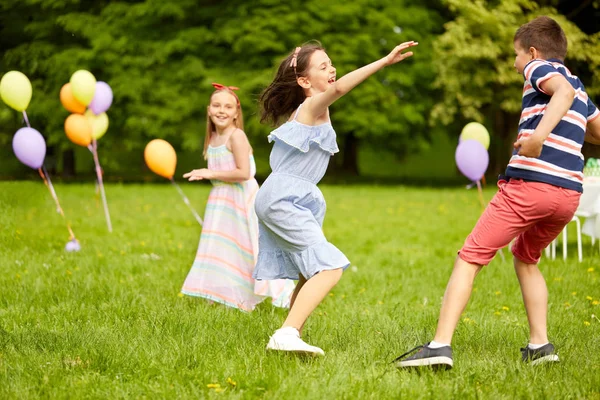 Счастливые дети играют в игру тегов на дне рождения — стоковое фото