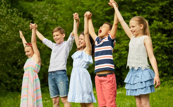 Счастливые дети с поднятыми руками в летнем парке — стоковое фото