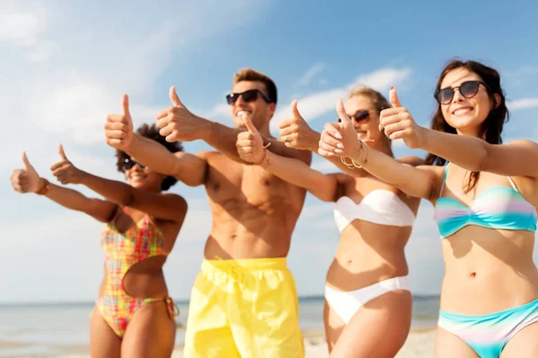 Amigos felices mostrando pulgares en la playa de verano —  Fotos de Stock