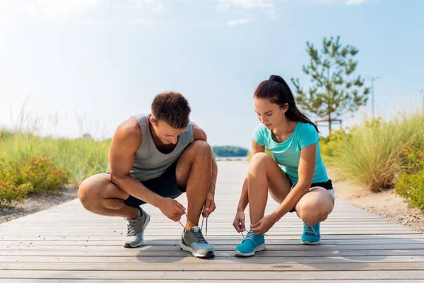 Couple of joggers tying sneakers shoelaces — Stock Photo, Image