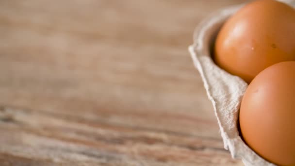 Закрытие яиц в картонной коробке на деревянном столе — стоковое видео