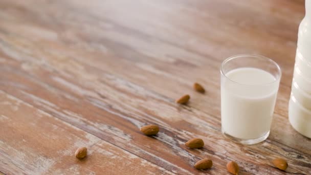 Leche sin lactosa y almendras sobre mesa de madera — Vídeo de stock