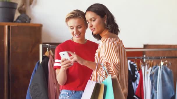 Mujeres con teléfono inteligente en la tienda de ropa vintage — Vídeos de Stock