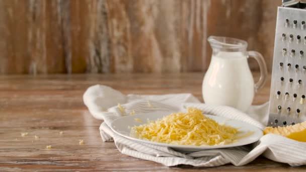 Primer plano de queso rallado y jarra de leche sobre la mesa — Vídeo de stock