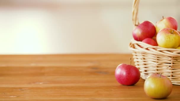 Dojrzałe jabłka w wiklinowym koszu na drewnianym stole — Wideo stockowe