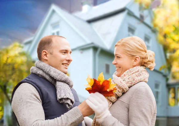 Casal sorrindo com folhas de bordo de outono sobre casa — Fotografia de Stock