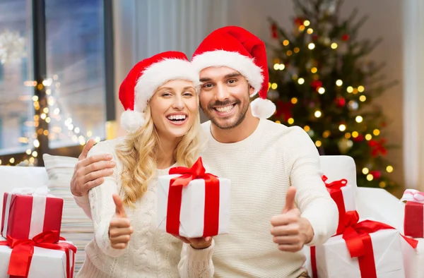 Счастливая пара с рождественскими подарками и большими пальцами вверх — стоковое фото