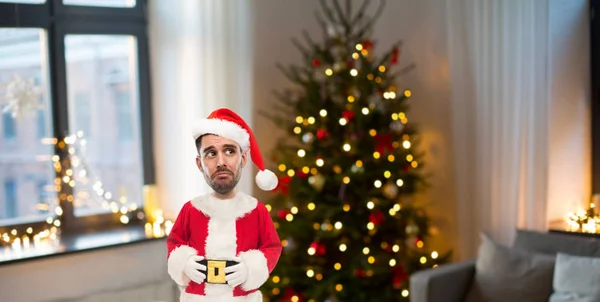 Hombre infeliz vestido de santa sobre el árbol de Navidad — Foto de Stock