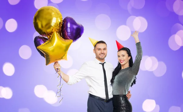 Счастливая пара с шапочками для вечеринок и воздушными шарами — стоковое фото