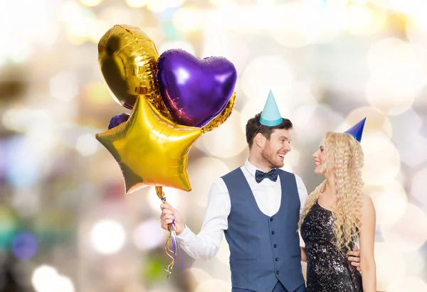 Couple heureux avec casquettes de fête et ballons — Photo