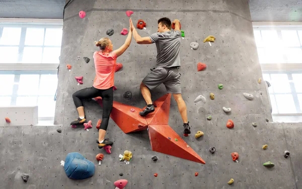Homme et femme escaladant un mur à la salle de gym intérieure — Photo