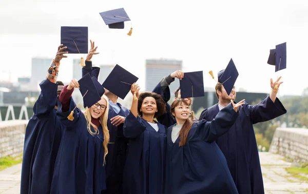 Laureati felici o studenti che lanciano assi di malta — Foto Stock