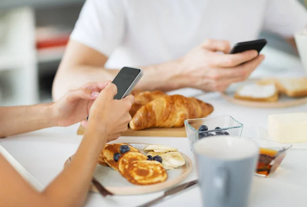 Nahaufnahme eines Paares mit Smartphones beim Frühstück — Stockfoto
