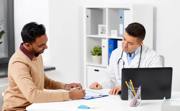Läkare med laptop och manlig patient på sjukhus — Stockfoto