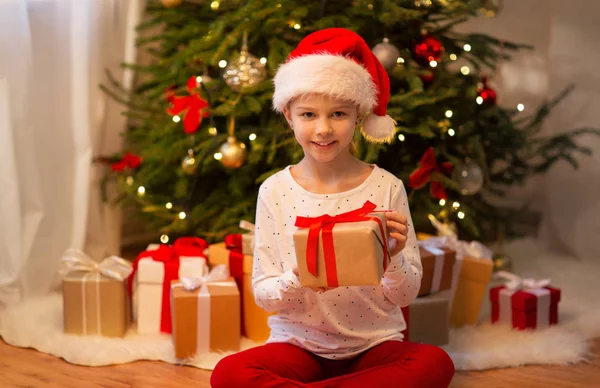 Sorridente ragazza in cappello di Babbo Natale con regalo di Natale — Foto Stock