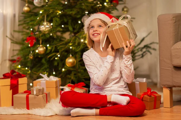 Χαμογελαστό κορίτσι με καπέλο santa με χριστουγεννιάτικο δώρο — Φωτογραφία Αρχείου